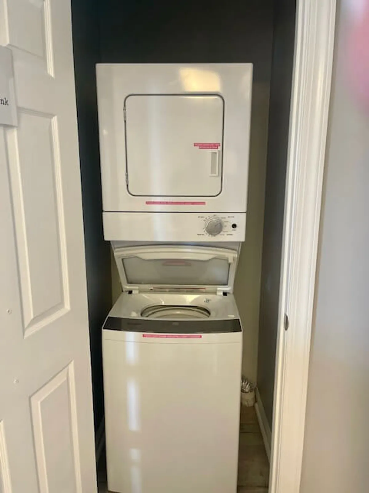 The image focuses on a stacked washer and dryer set neatly installed behind a door, emphasizing the convenience of in-unit laundry. The surrounding area is organized and practical, highlighting the ease of managing laundry tasks without leaving the comfort of your home.