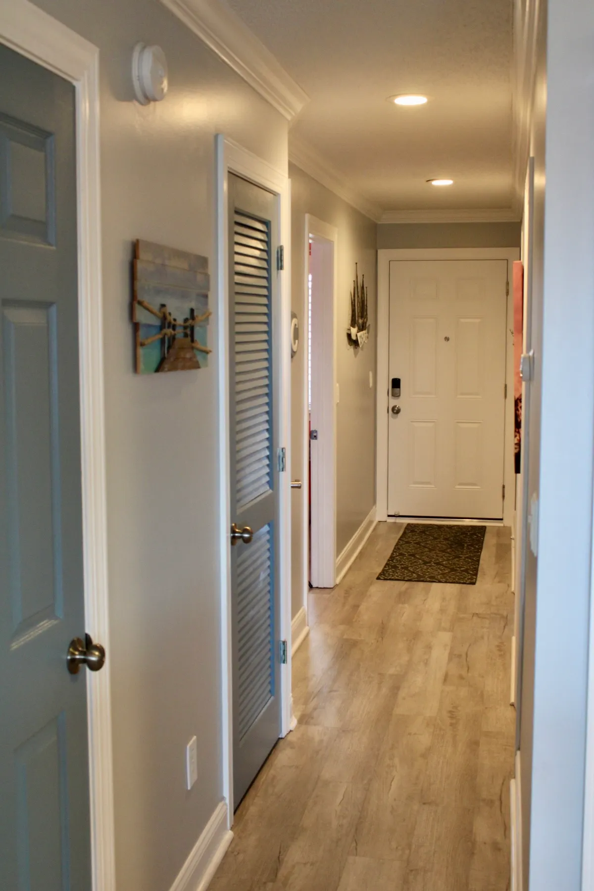 A warmly lit entrance area with a front door, decorative wall art, and stylish light fixtures. The scene hints at the transition from outdoor adventures to the comfort of home inside the resort community.